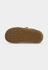Semelle en caoutchouc marron d’une chaussure d’enfant avec un motif de bande de roulement texturé et le numéro de taille 24 visible dans une section circulaire.