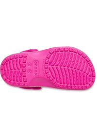 Suela de Crocs de color rosa brillante con patrón de textura y marcas de tamaño visibles.