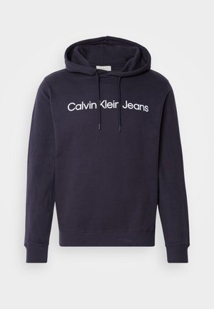 Navy blue hoodie made of cotton blend, featuring a front kangaroo pocket, drawstring hood, and white lettering: "Calvin Klein Jeans."