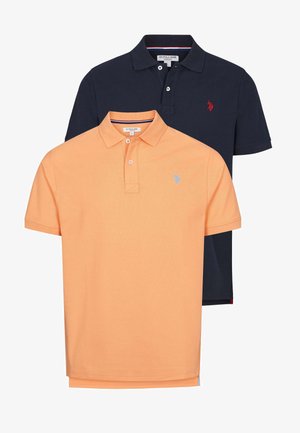 Dwie koszulki polo: jedna w pomarańczowym kolorze z jasnoniebieskim logo, druga w granatowym z czerwonym logo. Obie mają kołnierzyk i krótkie rękawy.