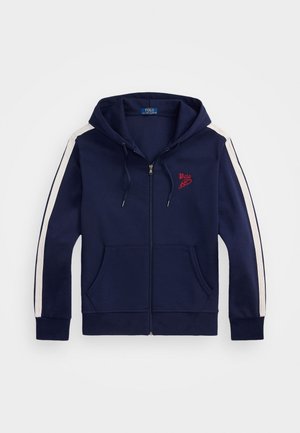 Granatowa bluza z kapturem na zamek z białymi paskami na rękawach, przednimi kieszeniami, regulowanym sznurkiem w kapturze oraz czerwonym logo Polo na piersi.