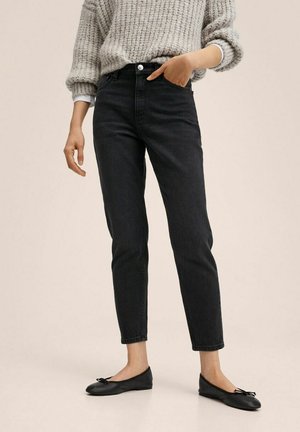 Jeans negros de tiro alto con un ajuste slim y cinco bolsillos, combinados con un suéter de punto gris claro y bailarinas negras con un lazo.