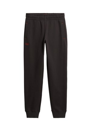 Pantalon de jogging noir avec ceinture élastique, poches latérales avec coutures rouges, poignets côtelés aux chevilles, et petit logo rouge sur la cuisse gauche.