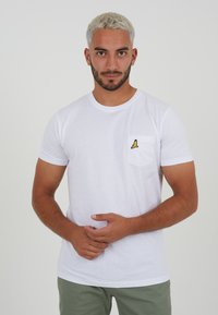 White cotton t-shirt featuring a front pocket with yellow banana embroidery. Short sleeves, crew neck, and regular fit design.