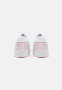 Baskets Puma avec une tige en suède gris, accent en tissu blanc et détails en rose au niveau du talon. Texture lisse avec des coutures et logo de la marque à l'arrière.