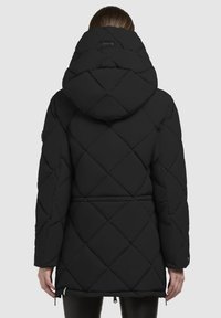 Must mustaga nurkidega must jakk, millel on suur kapuuts, teemantkujuline õmblus, elastsed mansetid ja reguleeritav äärepael.