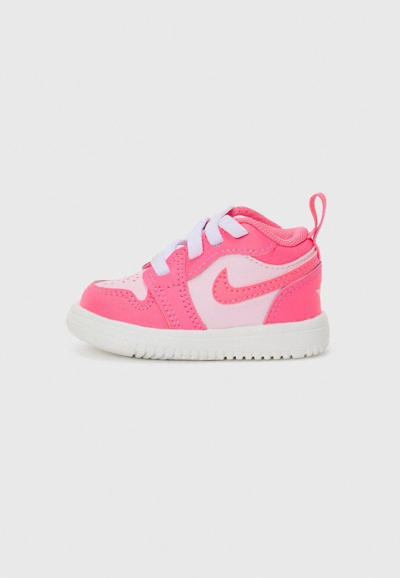 Pink Nike kids' sneaker with white accents, round toe, lace-up closure, and textured rubber sole. Features a pull tab at the back.