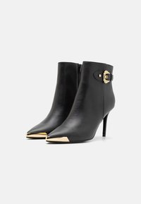 Μαύρες δερμάτινες μπούτσε άγριας περικοπής με αιχμηρές μύτες, χρυσή λεπτομέρεια στη μύτη, φερμουάρ στο πλάι και διακοσμητική αγκράφα στο πλάι. Τακούνι στιλέτο.