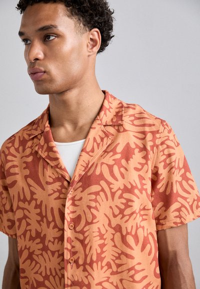 Short-sleeve shirt in orange fabric with a bold abstract pattern in lighter orange. Features a collared neck and button front.