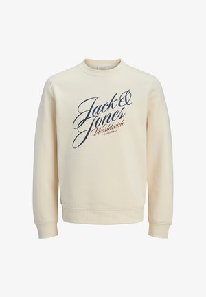 Sudadera de color crema con cuello redondo, mangas largas y puños acanalados. Presenta un logo en escritura azul marino en el frente. Textura suave.