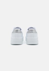 Sneakers bianchi con tomaia in pelle liscia, punta arrotondata, colletto imbottito e un accentuazione in logo argentato sul tallone. Suola in gomma spessa.