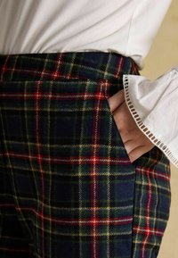 Vilnas svārki ar zilas, zaļas, sarkanas un dzeltenas krāsas rūtainu rakstu, sānu kabatu un teksturētu, siltu apdari.