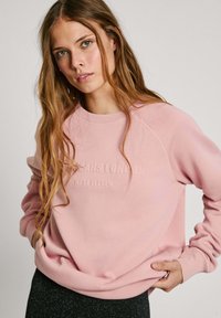 Felpa rosa con polsini e orlo a coste, caratterizzata da una stampa in rilievo con la scritta "Jeans London West Eleven" sul fronte. Tessuto morbido, vestibilità comoda.
