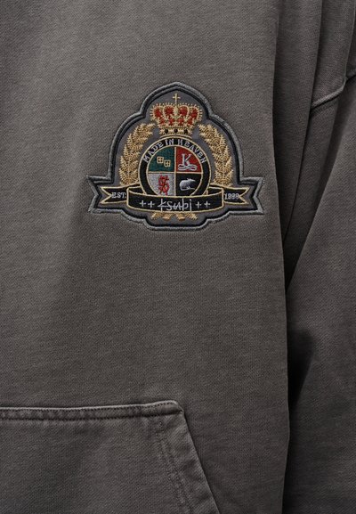 Γκρι φούτερ με κεντημένο έμβλημα που περιλαμβάνει κορώνη, φύλλα δάφνης και διάφορα έγχρωμα διακριτικά. Διαθέτει τσέπη μπροστά.