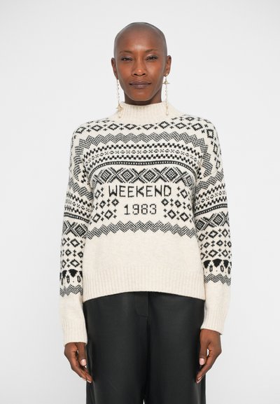 Pull en maille épaisse crème avec des motifs géométriques noirs, arborant "WEEKEND 1983" au centre, avec des poignets et un ourlet côtelés.