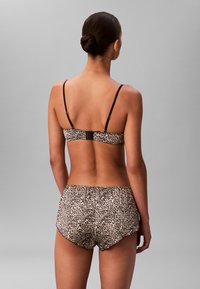 Komplet bielizny w cętki z miękkiej tkaniny; zawiera cienkie, regulowane ramiączka, marszczony pasek w talii oraz zaokrąglony dół.