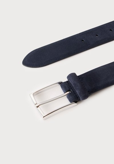 Ceinture en daim bleu foncé avec une boucle rectangulaire argentée, montrant la pointe de la ceinture et les trous de réglage sur un fond clair.