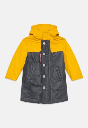 Impermeabile giallo con cappuccio e corpo grigio, dotato di bottoni argentati, due tasche frontali e un'etichetta con il logo. Realizzato in materiale impermeabile.