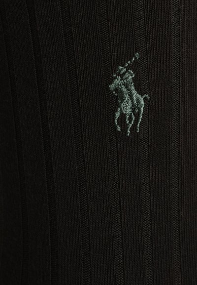 Juodas raukšlėtas audinys kojinės, su žaliu siuvinėtų logotipu, vaizduojančiu polo žaidėją ant arklių.