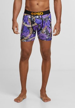 Lilla mønstrede boxershorts med en sort elastik med mærkenavnet "PSD." Designet inkluderer roser og kædemotiver over stoffet.