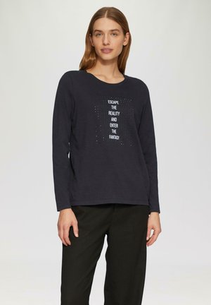 T-shirt à manches longues de couleur bleu marine foncé avec un col rond, affichant un design de texte blanc et de points au centre. Tissu doux, coupe décontractée.