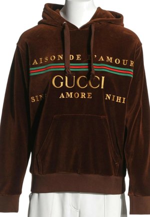 Bruine fluwelen hoodie met voorzak en gouden tekst "Maison de l'Amour Gucci Amore" en rode en groene strepen over de borst.