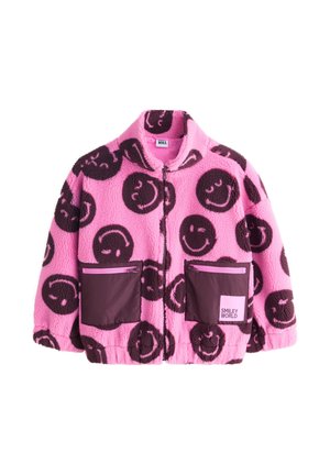 Rosa Fleecejacke mit großen dunklen Smiley-Gesichtern, zwei vorderen Reißverschlusstaschen und einem „Smiley World“-Etikett auf der rechten Tasche.