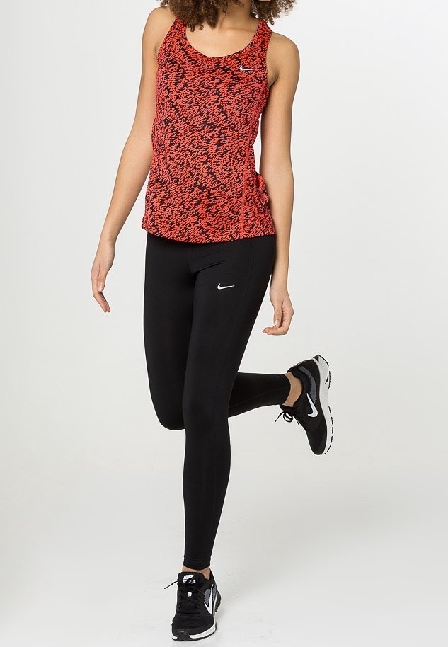 Débardeur rouge et noir à motifs avec un col rond, associé à des leggings noirs et des chaussures de sport noires. Logos Nike bien visibles sur les vêtements.