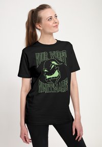 Czarny bawełniany T-shirt z zielonym nadrukiem graficznym z napisem "YOUR WORST NIGHTMARE" i stylizowaną twarzą. Krótkie rękawy, luźny fason.