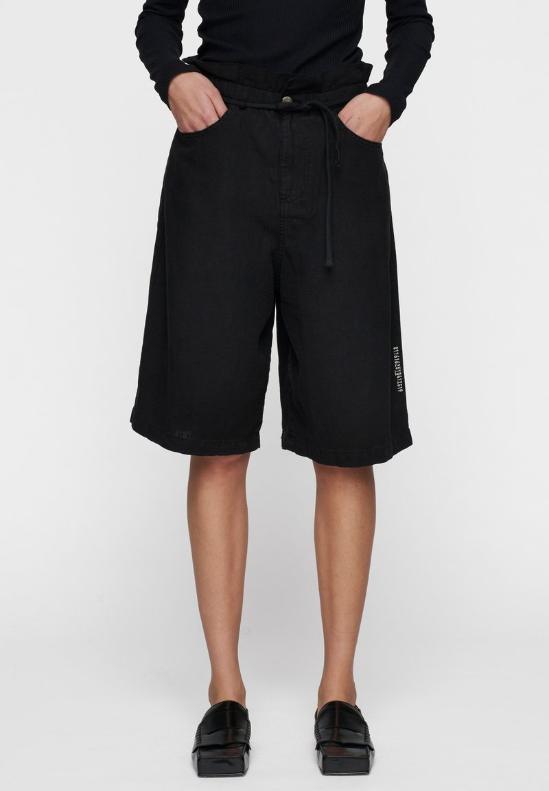 Zwarte shorts met een trekkoord in de taille, twee zijzakken, een losse fit en een logo detail op het onderbeen. Gemaakt van een gestructureerde stof.
