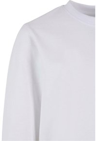 Prim-plan al unui tricou alb simplu cu mâneci lungi, care arată umărul, partea superioară a brațului și decolteul rotund cu textură fină a țesăturii.