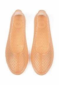 Transparent, diamond-patterned flats in light peach, featuring a smooth texture and rounded toe design with a cushioned insole.