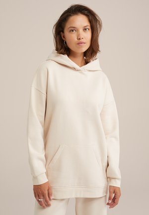 Sudadera con capucha beige, con un bolsillo frontal, mangas largas y puños acanalados. Tejido suave con un corte holgado y un diseño sencillo.