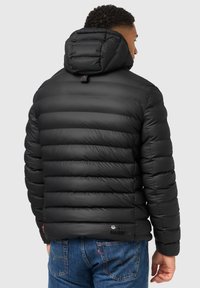 Chaqueta de plumas negra con capucha, que presenta secciones acolchadas horizontales, una textura suave y un pequeño logo en el dobladillo.