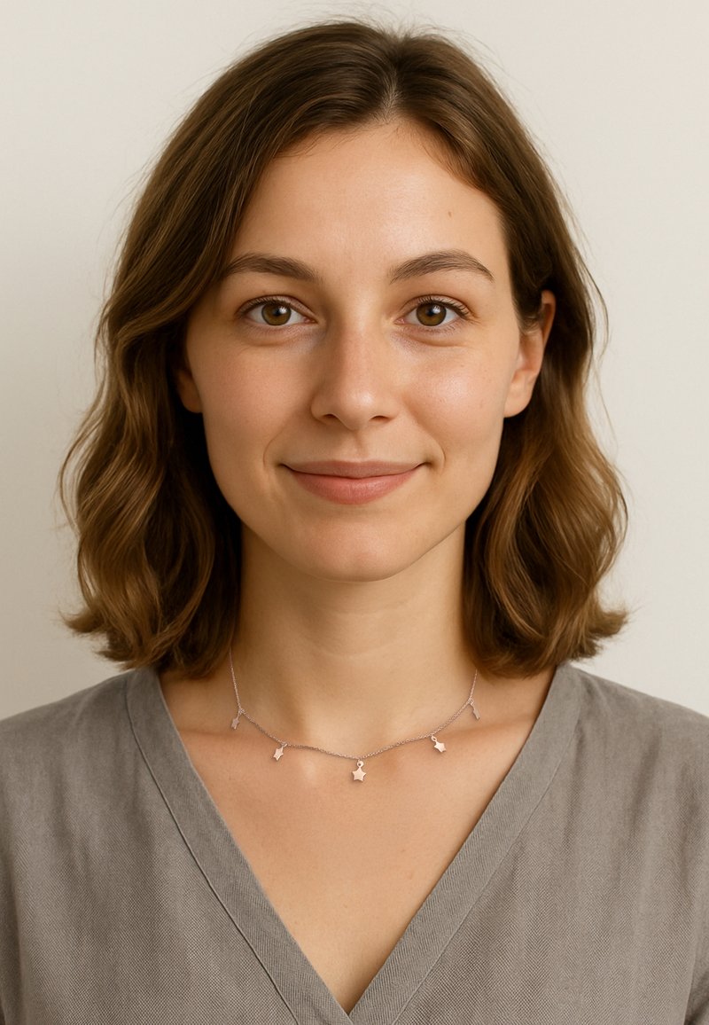 Sart sølv halskæde med fem stjernesformede pendanter, der har en fin kæde. Modellen bærer en grå v-hals top. Neutral baggrund.