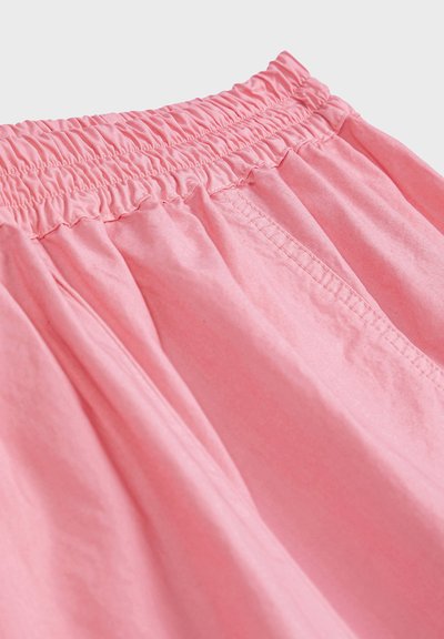 Shorts avec taille élastique rose, coutures froncées et couture visible de la poche latérale, en tissu léger.