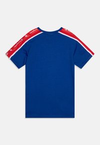 Camiseta azul de manga corta con acentos a rayas rojas y blancas en los hombros. Fabricada en suave algodón con cuello redondo.