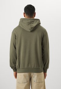Hætte sweatshirt i olivengrøn, lavet af blødt stof, med en afslappet pasform, ribbede manchetter og søm. Set fra ryggen, ingen synlige grafikker.