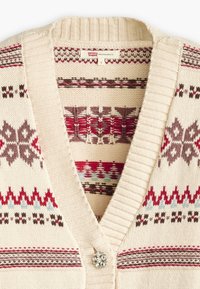 Beige knitted cardigan with a V-neck, featuring red and brown geometric patterns and a jeweled button at the neckline.