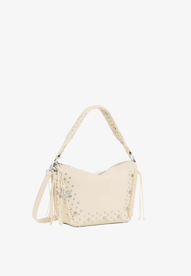 Sac à épaule couleur crème avec poignée tressée, ornements en clous argentés, pampilles latérales et bandoulière amovible, sur fond blanc.