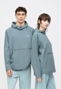 Letvægts, hættetrøjer i blødt blåt stof. Har en frontlomme og elastiske snore i hætten for justerbarhed.