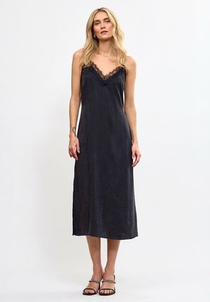 Czarna satynowa sukienka na ramiączkach z koronkowym wykończeniem przy dekolcie, o długości do połowy łydki, gładka w dotyku, z cienkimi ramiączkami. Prosta i elegancka sylwetka.