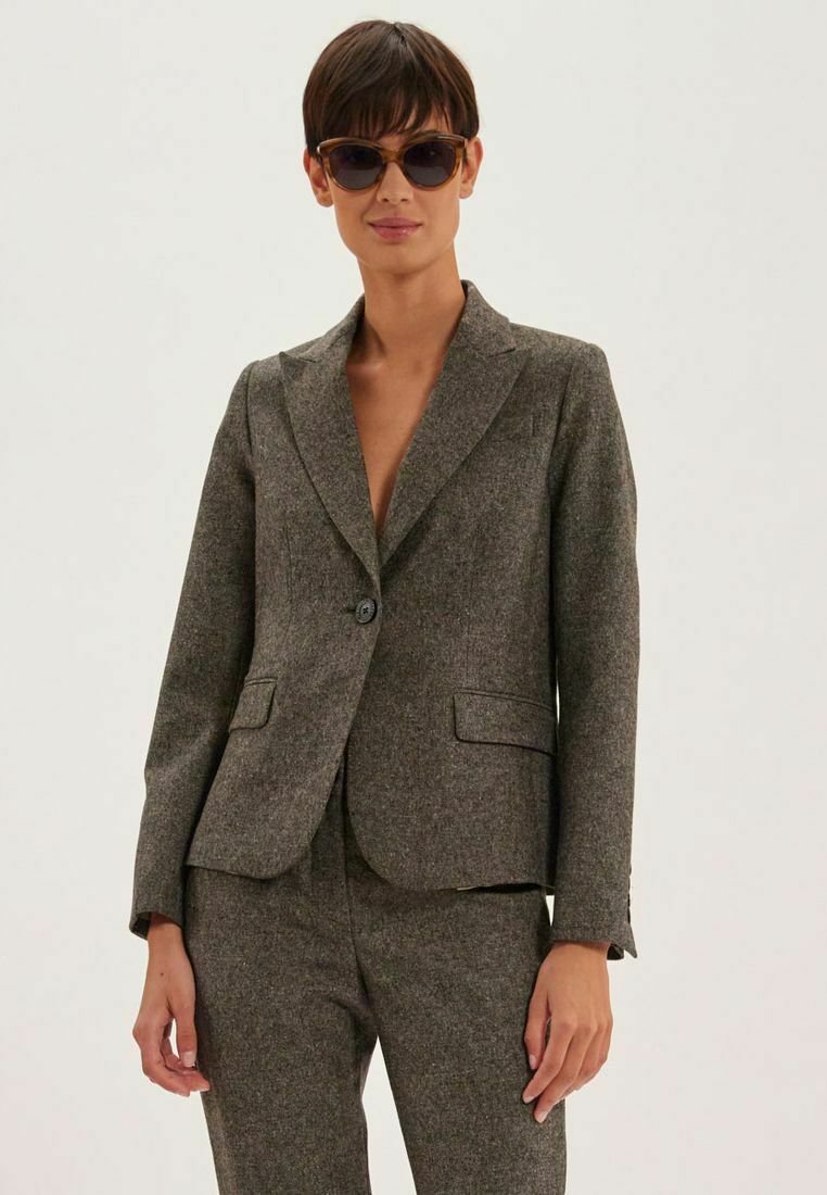 Blazer en mélange de laine texturé marron avec un revers cranté, fermeture à bouton unique et deux poches avant. Associé à un pantalon assorti.