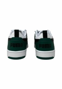 Zapatillas verdes y blancas con una textura de cuero suave, con detalles en negro y el logo "PUMA" en el talón, suela de goma blanca plana.