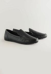 Mocassins en cuir noir avec texture crocodile, design à enfiler, bout arrondi et détails de couture contrastants sur le devant et les côtés.