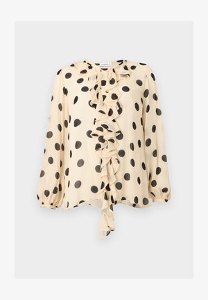 Krémeľová blúzka s dlhým rukávom, veľkými čiernymi bodkami a stredným kaskádovým volánom na prednej strane.