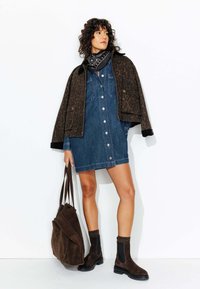 Veste en imprimé léopard marron, robe chemise en denim bleu avec boutons, écharpe noire, bottes en suède marron avec côtés élastiques, sac fourre-tout marron foncé.