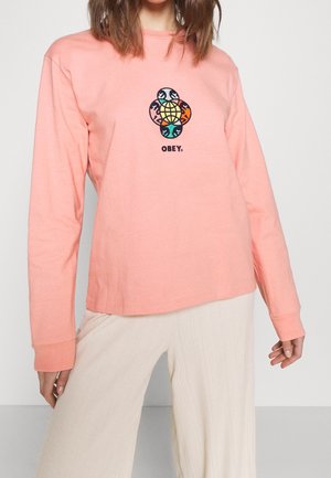 Långärmad, korallfärgad t-shirt i bomull med en central flerfärgad grafik och texten "OBEY" under. Mjuk textur med en avslappnad passform.