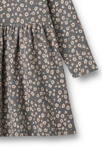Bloemenprint jurk in blauw-grijze stof, met lange mouwen en een gathered taille. Kleine, lichtgekleurde bloemen creëren een herhalend patroon.