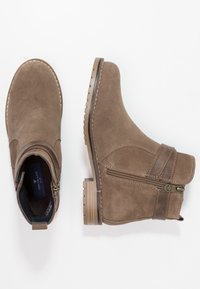 Bottines en daim marron avec une fermeture éclair latérale, des accents cousus et une semelle texturée durable. Bout arrondi et talon bas empilé.